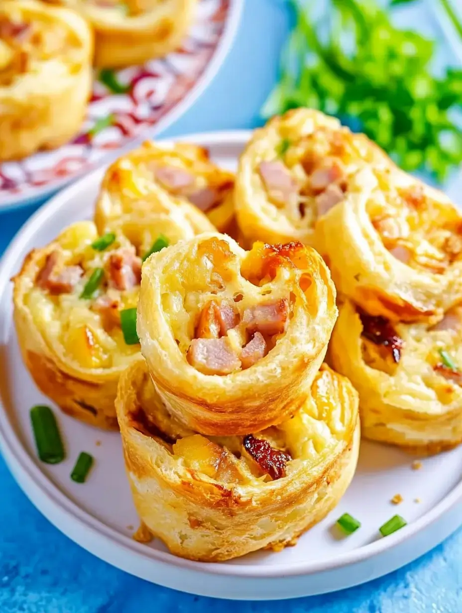 Golden pastry pinwheels stuffed with diced ham and cheese, topped with green onion pieces on a serving dish.